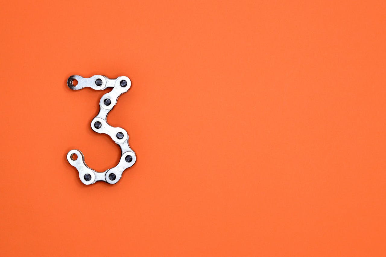 Bright orange background with number 3 made using a bicycle chain
